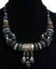 Collier ethnique artisanal imitation pierres noires difformes agrementees de perles noires et de breloques gravees argentees