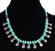 Collier ethnique artisanal imitation pierres bleues-vertes claires agrementees de perles bleues et argentees et de breloques en spiral
